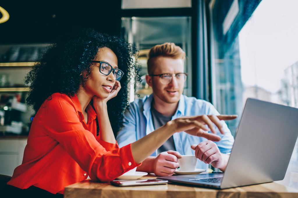 Two people discussing plans while looking at a laptop.